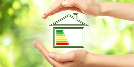 Kuća sa skalom energetske efikasnosti okružena zelenilom kao simbol racionalne potrošnje energije u kući