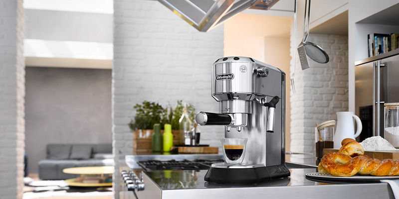 Na radnoj ploči u kuhinji nalazi se Delonghi aparat za espresso i šolja sa pripremljenim espressom.