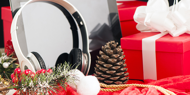 Slušalice i tablet pored novogodišnjih poklona u prazničnoj dekoraciji