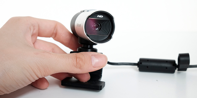 Devojka rukom podešava postolje web kamere crno-sive boje sa USB kablom