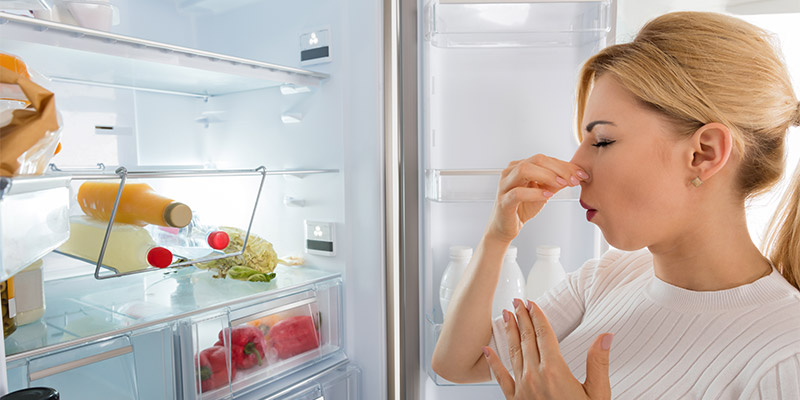 Žena oseća neprijatan miris iz frižidera