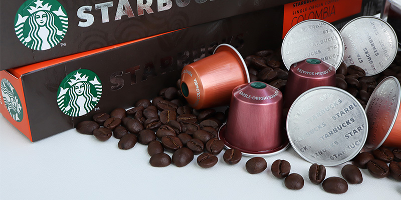 Pored pakovanja za Starbucks kapsule nalazi se i nekoliko manjih kapsula između kojih su poređana i zrna kafe