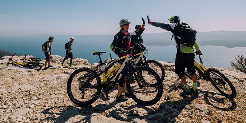 Mnoštvo prijatelja popeli su se na vrh planine Greyp električnim biciklama, čestitaju jedni drugima i uživaju u pogledu sa planine na more