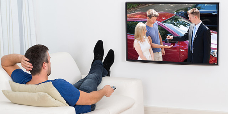 Mlad muškarac sa optimalne udaljenosti gleda televizor okačen na tv nosač