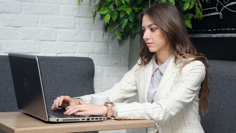 Devojka sedi u kancelariji za radnim stolom i obavlja zadatke na HP laptopu