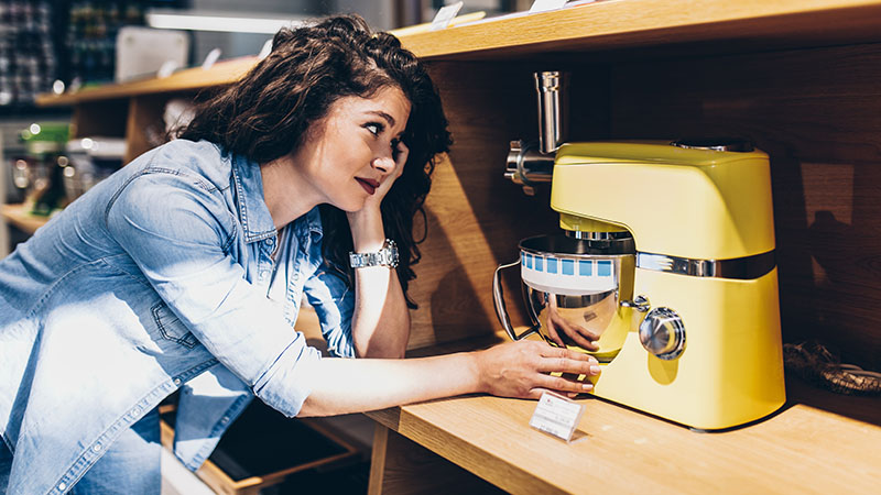 Mlada devojka kupuje kuhinjski robot žute boje