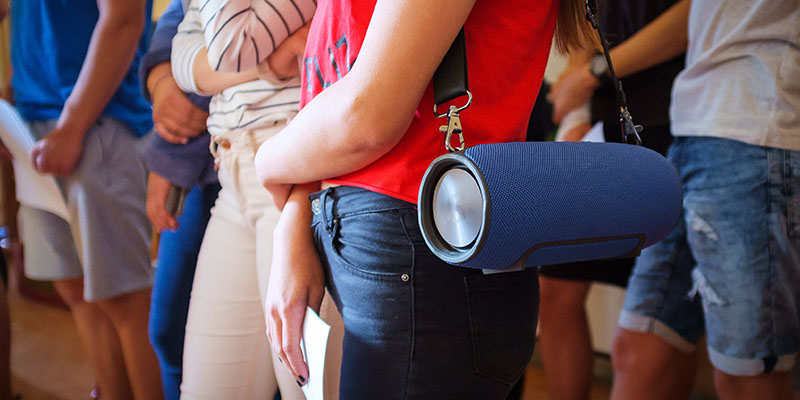 Plavi Bluetooth zvučnik okačen na rame devojke
