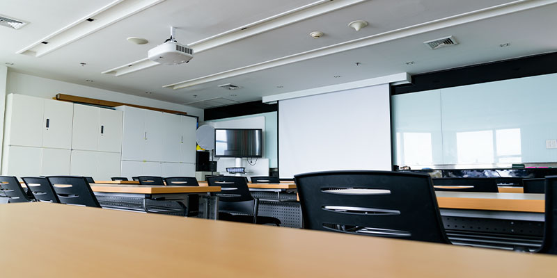 Učionica sa stolovima, stolicama, projektorom i projektorskim platnom na izvlačenje